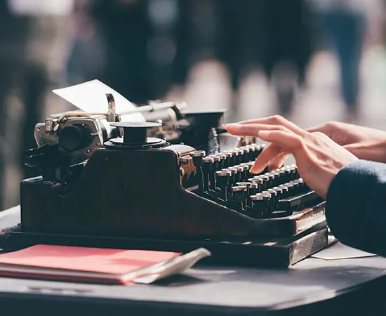 ChatGTP taking over. Image shows a someone typing on a typewriter with a blurry crowd of people in the background