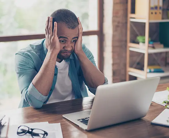 Man holding face at laptop